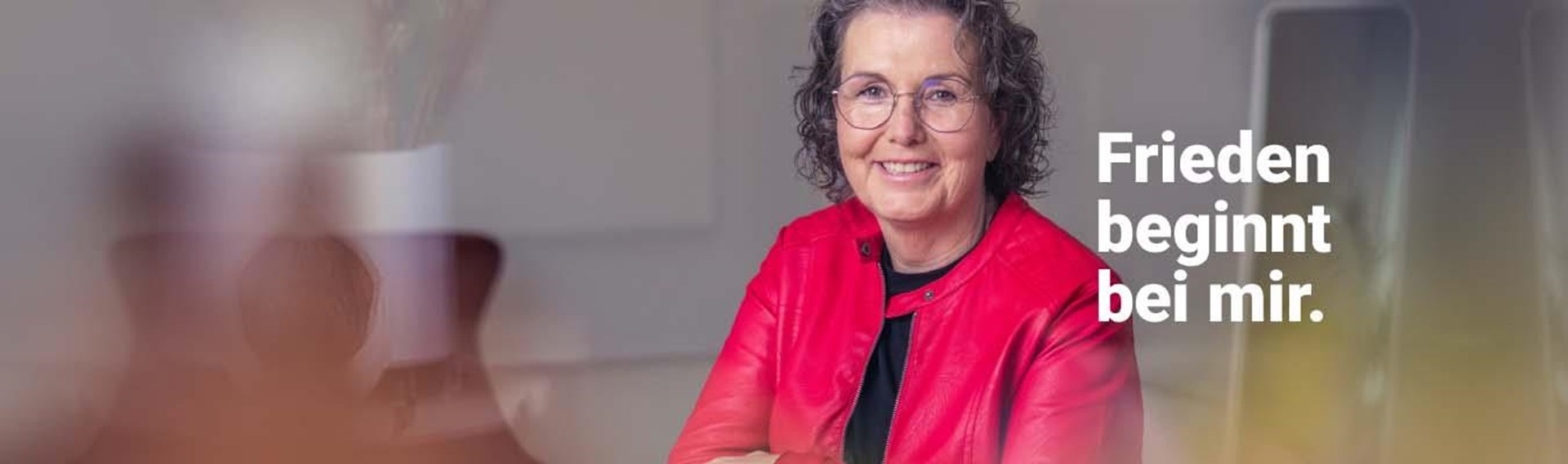 Eine Frau mit grauen gelockten Haaren und Brille mit der Aufschrift "Frieden beginnt bei mir."
